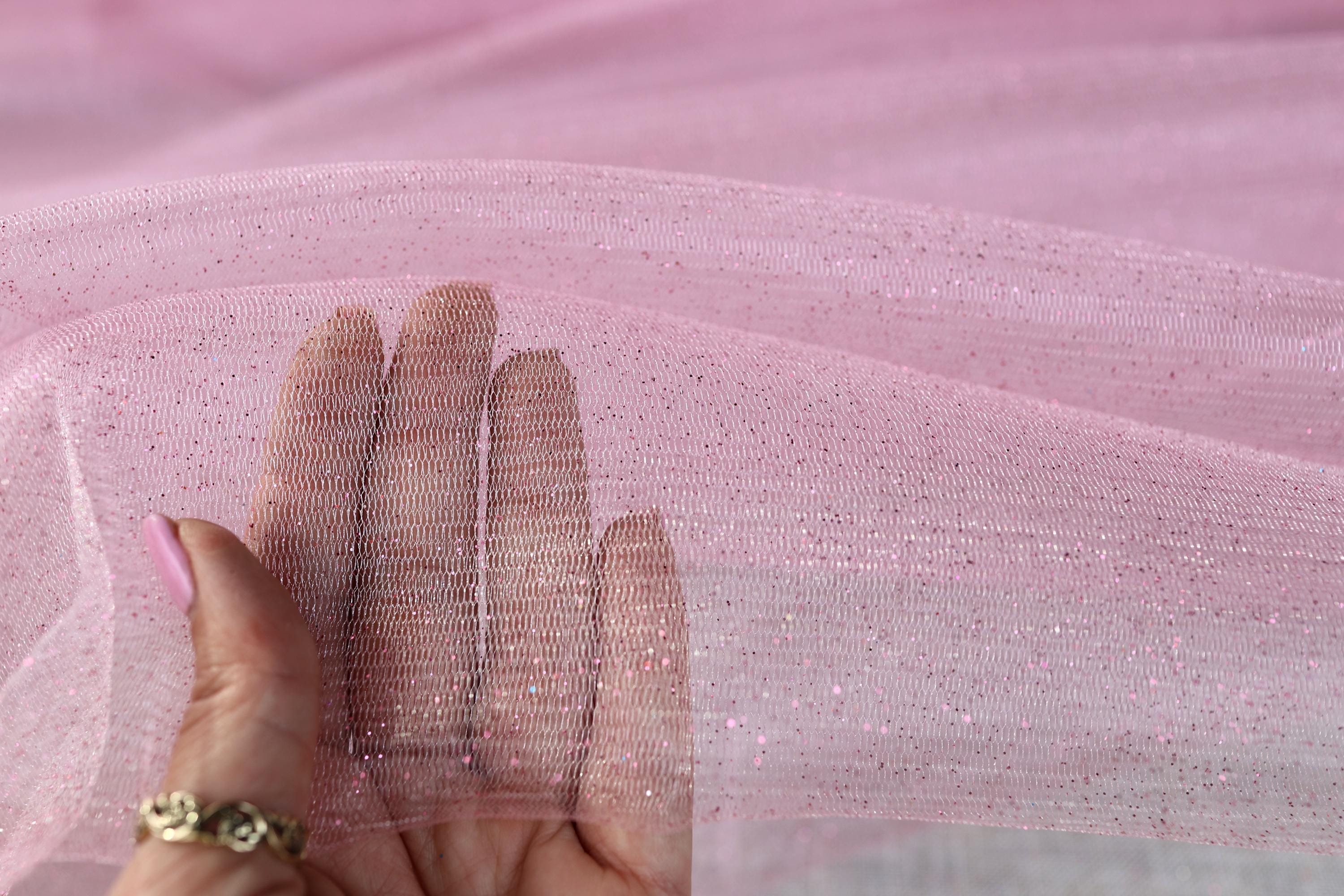a woman's hand holding a piece of pink fabric
