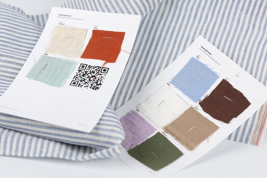 two pieces of paper with fabric swatches and QR codes, placed on a striped fabric background.