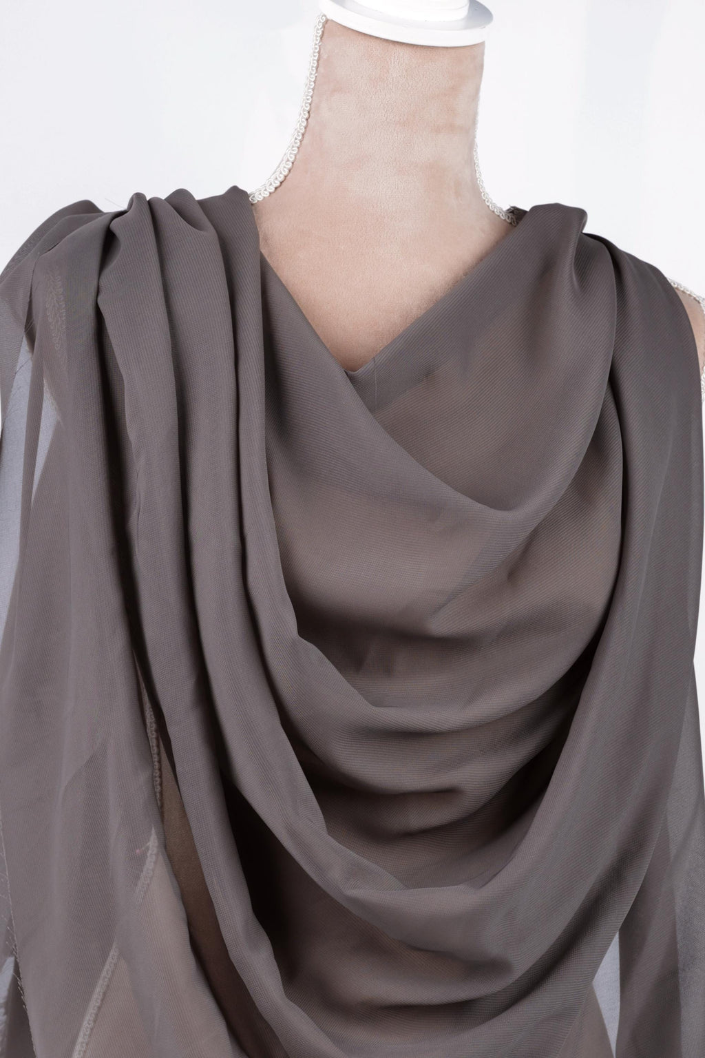 A mannequin wearing a gray draped fabric draped over its body.