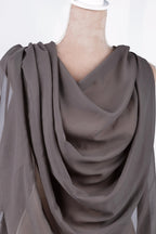 A mannequin wearing a gray draped fabric draped over its body.