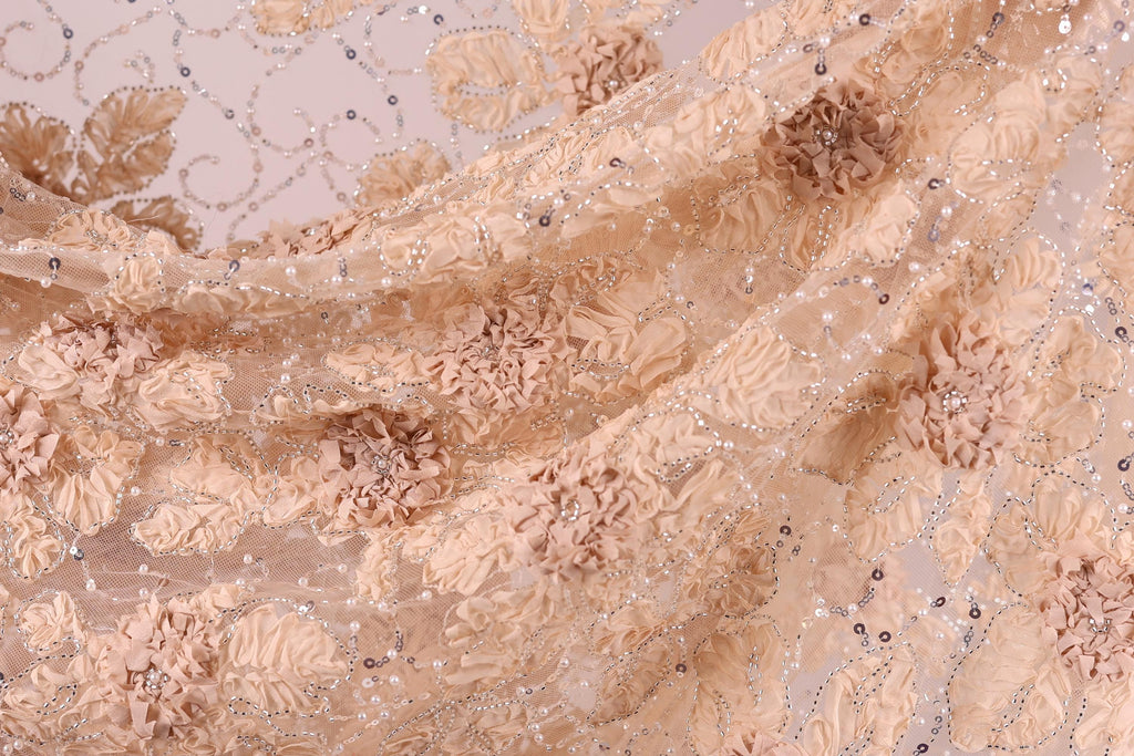 The image is a close-up of a delicate, intricately embroidered fabric with a floral pattern. The fabric appears to be made of a light-colored material, possibly lace or chiffon, with a floral design that includes small flowers and leaves. The fabric is folded and crumpled, giving it a soft and delicate appearance.