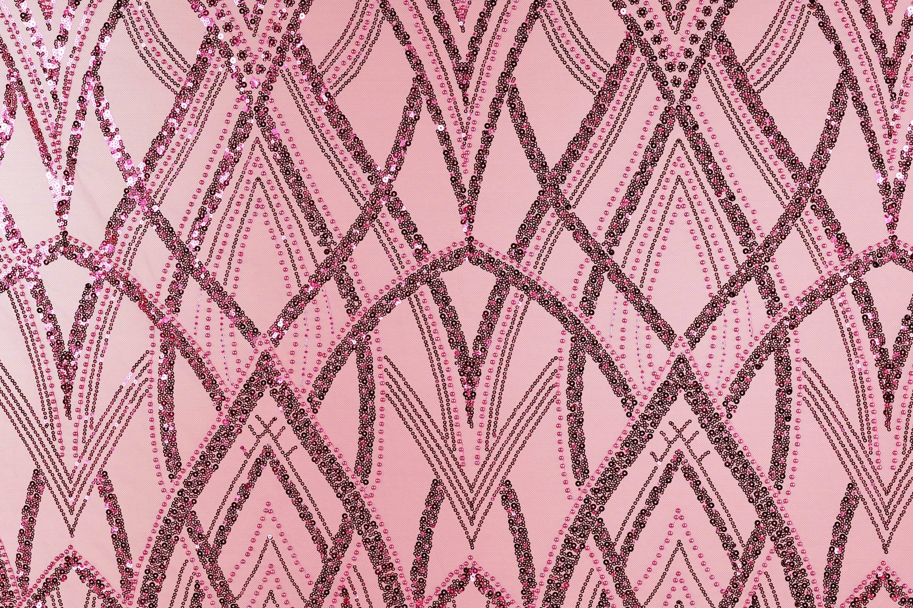a close-up view of a pink fabric with a repeating pattern of black and pink lines and dots, creating a visually striking and intricate design.