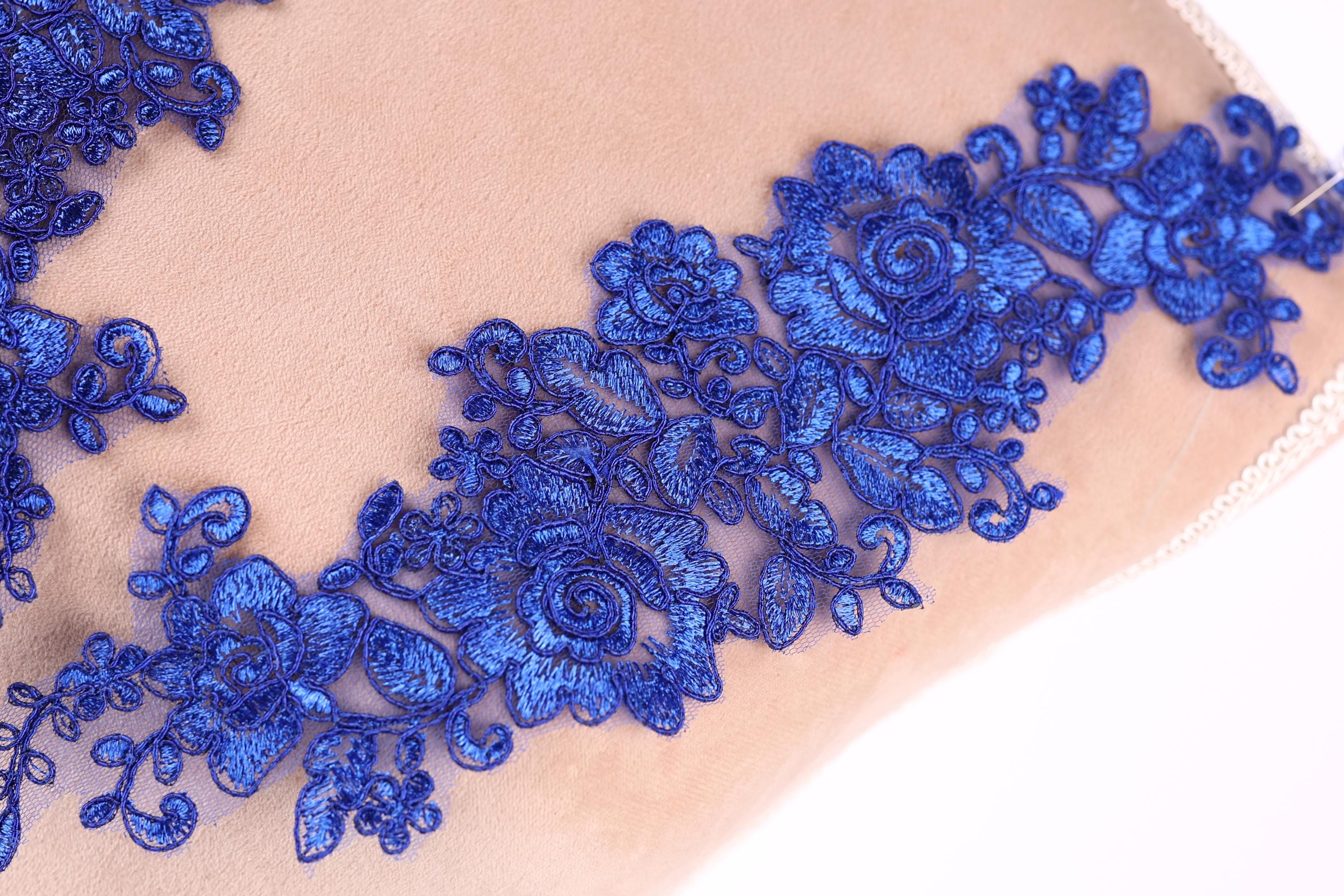 a close-up view of a fabric with a delicate blue floral embroidery design.