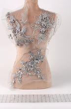 a mannequin with a beige body and a white background. The mannequin is adorned with silver floral and leaf designs, creating a visually striking contrast against the white background.