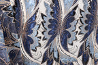 a close-up view of a fabric with a repeating pattern of blue and white floral designs, accented with gold and black sequins.