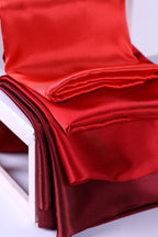 a close-up view of a red satin fabric, possibly a satin chair cushion or a red fabric draped over a chair.
