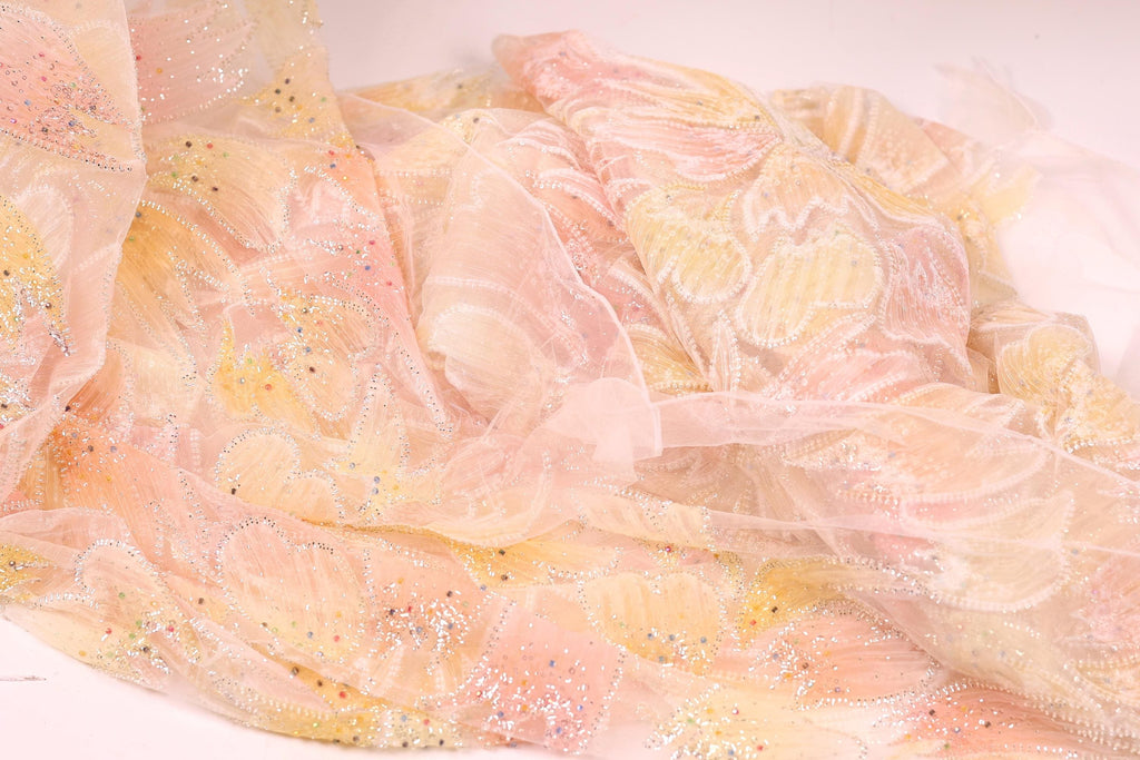 a close-up view of a delicate, sheer fabric with a floral pattern in shades of pink and yellow. The fabric appears to be made of sheer material, giving it a soft and delicate appearance.