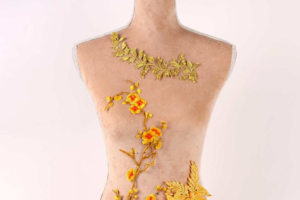 A mannequin with a floral design on its torso, featuring yellow flowers and leaves.