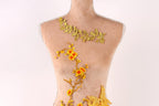 A mannequin with a floral design on its torso, featuring yellow flowers and leaves.
