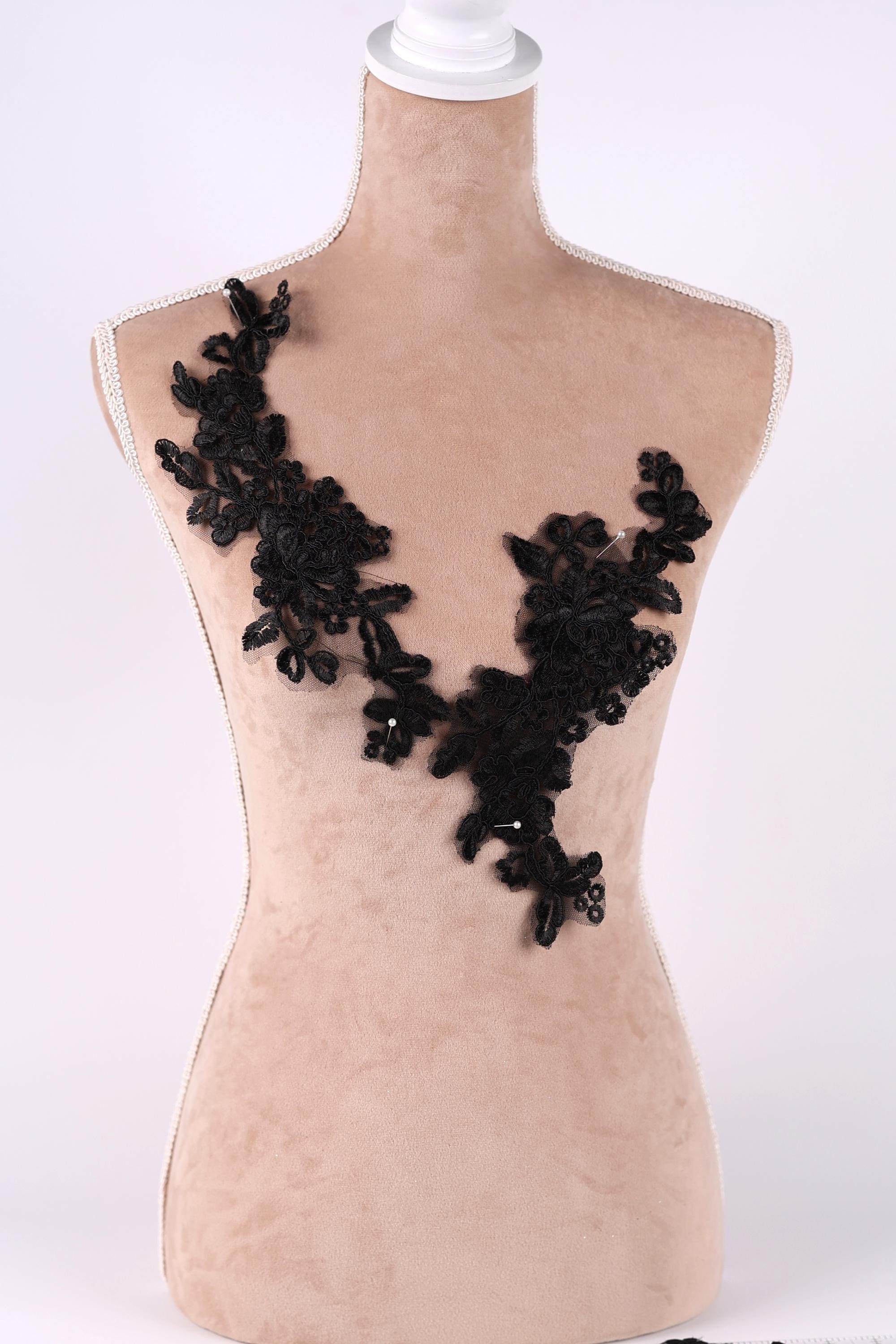 A mannequin with a beige body and black lace or floral embellishments on its chest area.