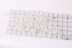 a clear ruler with a delicate white lace design placed on it.