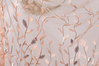 a close-up view of a delicate, sheer fabric adorned with a repeating pattern of small, intricately designed leaves in shades of brown and beige. The leaves appear to be made of sequins or beads, adding a touch of sparkle and texture to the fabric. The fabric is draped over a surface, creating a visually appealing and delicate appearance.