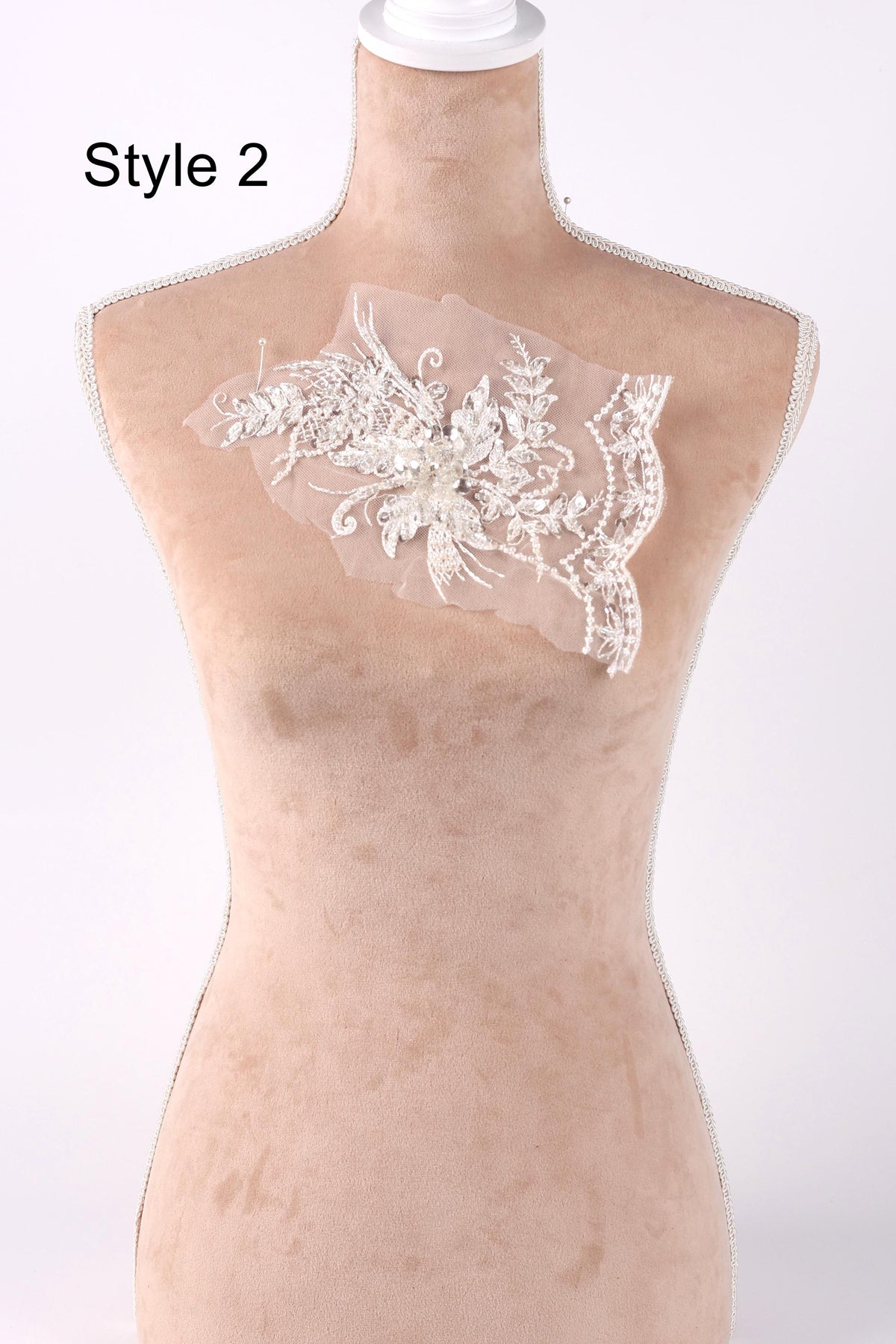 A mannequin with a decorative lace piece on its chest, displayed against a plain background.