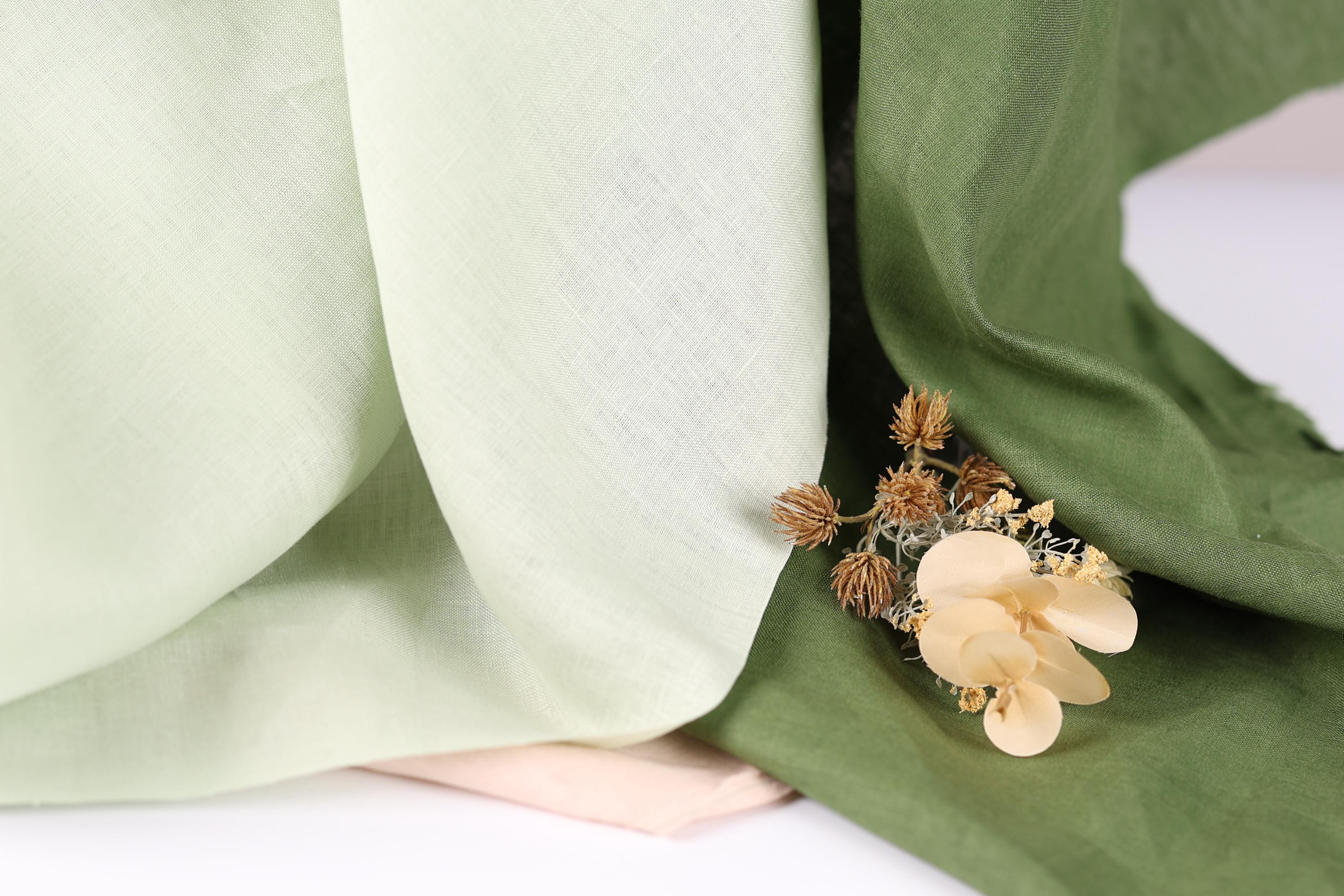 a close-up view of a green fabric with a delicate flower resting on it.