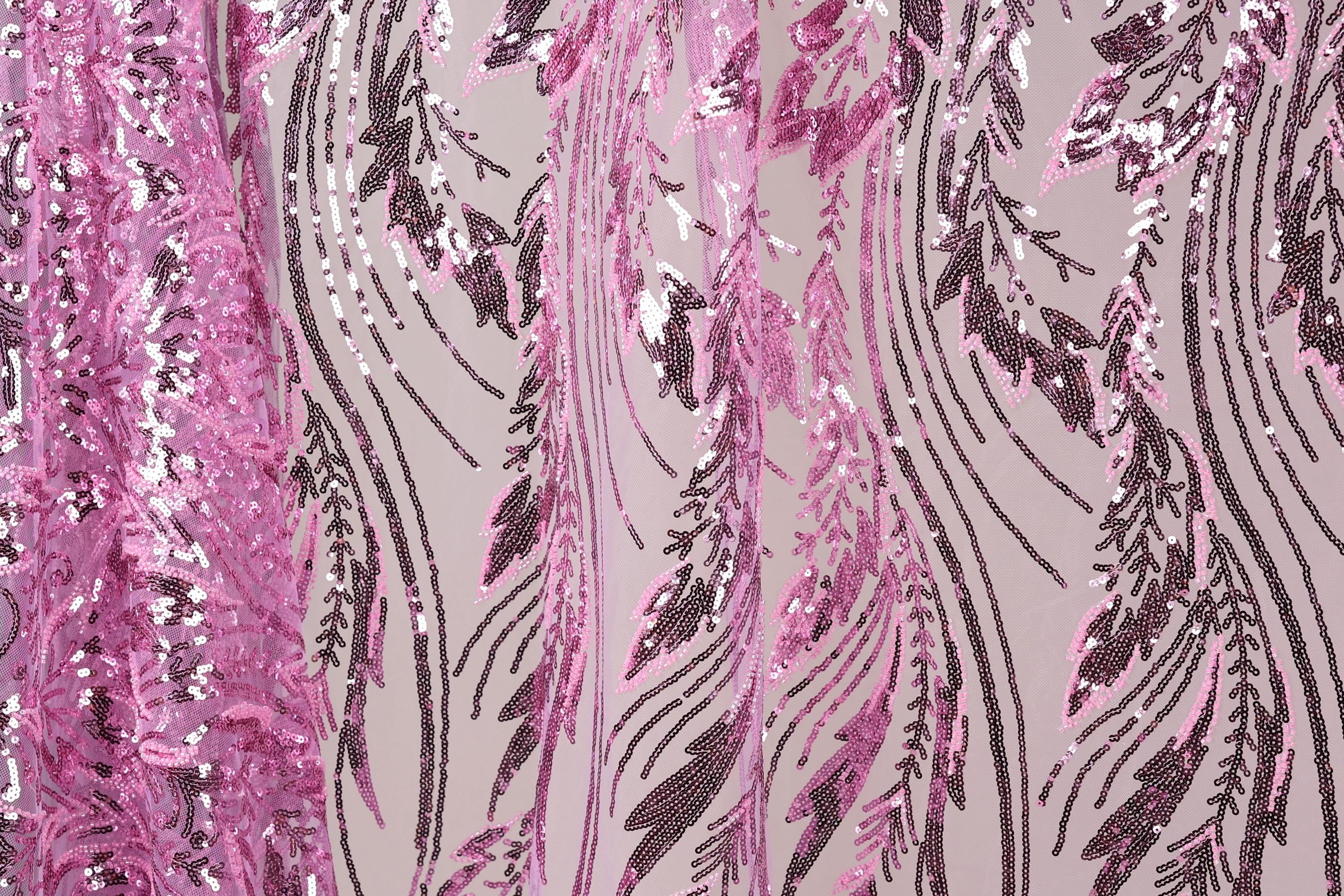 a close-up view of a fabric with a pink and purple sequin pattern. The fabric appears to be a sheer material, with the pink sequins arranged in a zigzag pattern and the purple sequins forming a repeating pattern. The fabric has a textured appearance, with the pink sequins appearing more densely packed than the purple ones. The overall design of the fabric is visually striking and eye-catching.