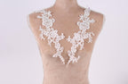 A mannequin wearing a white lace dress with intricate floral patterns.