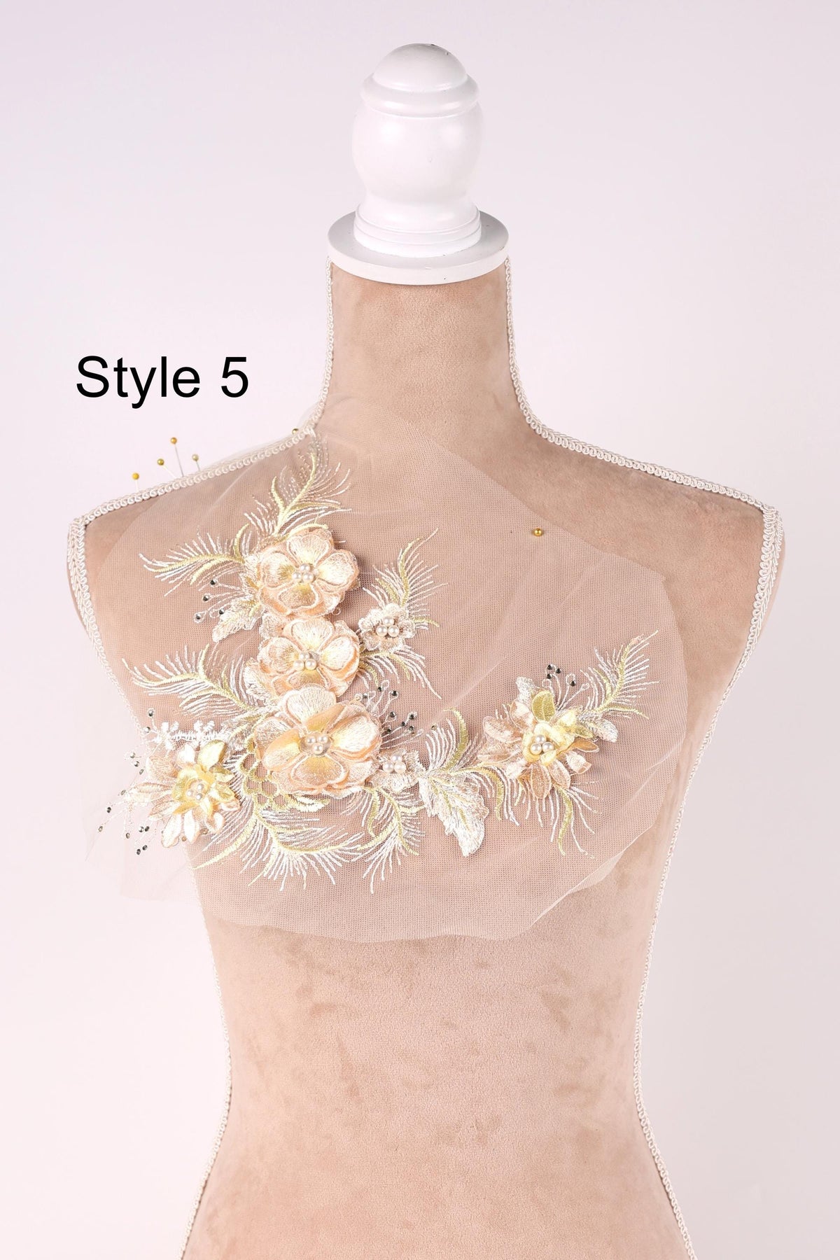 A mannequin with a decorative floral piece on its bust, featuring a combination of white and peach flowers.