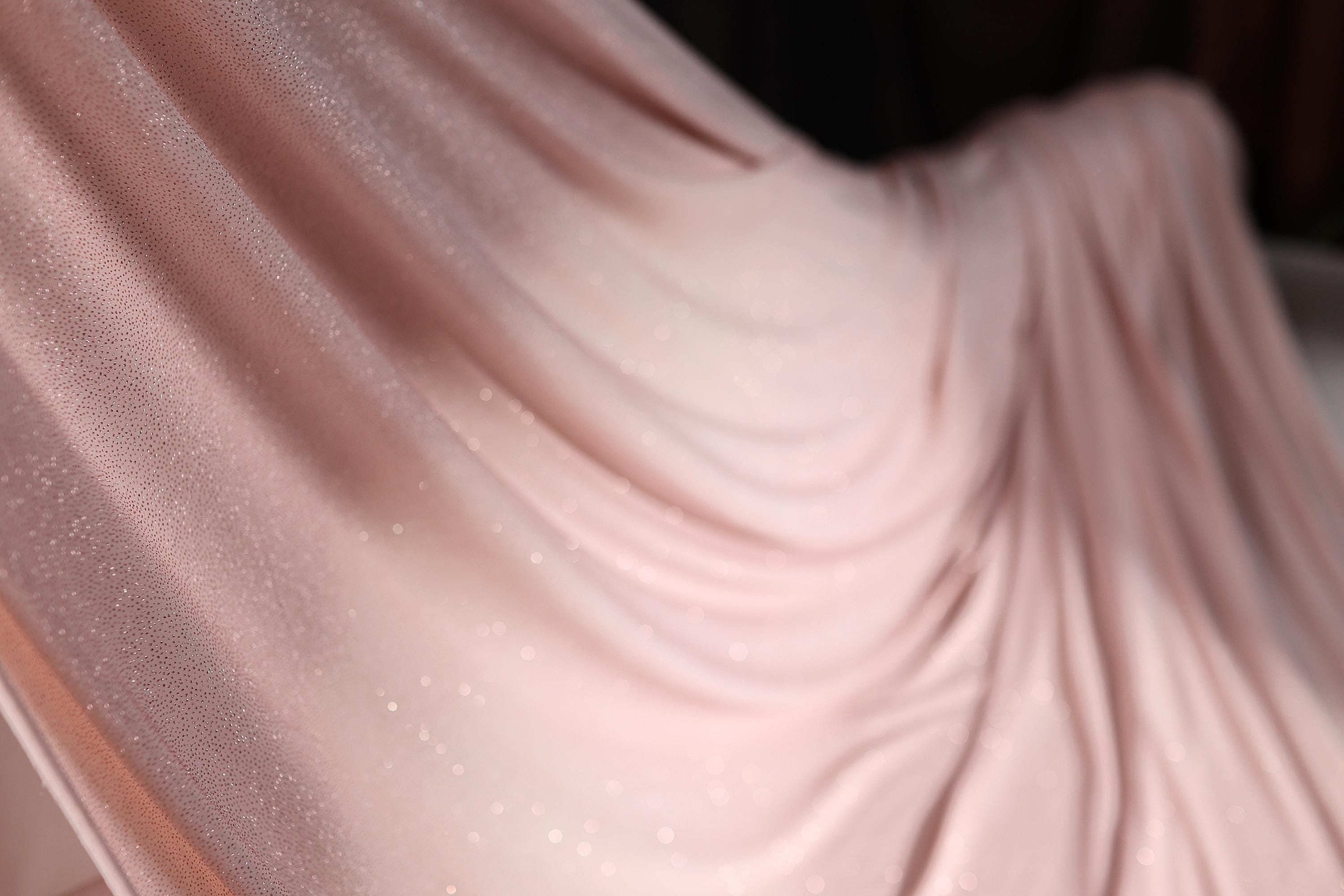 a woman in a pink dress standing in front of a curtain