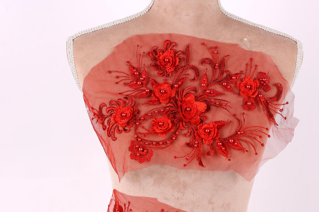 A mannequin wearing a red dress with intricate floral embroidery on the front.