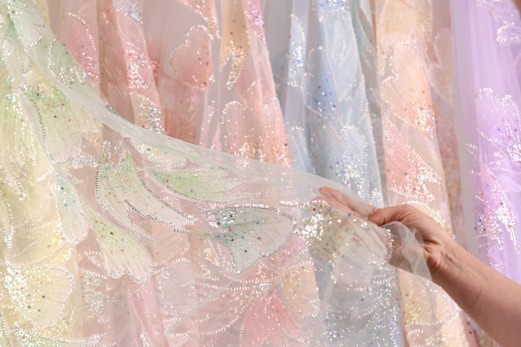 A hand is holding up a piece of fabric with a colorful, patterned design, likely a piece of clothing or textile.