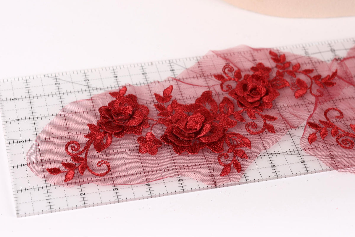 a close-up view of a clear ruler with red floral embroidery designs on it.