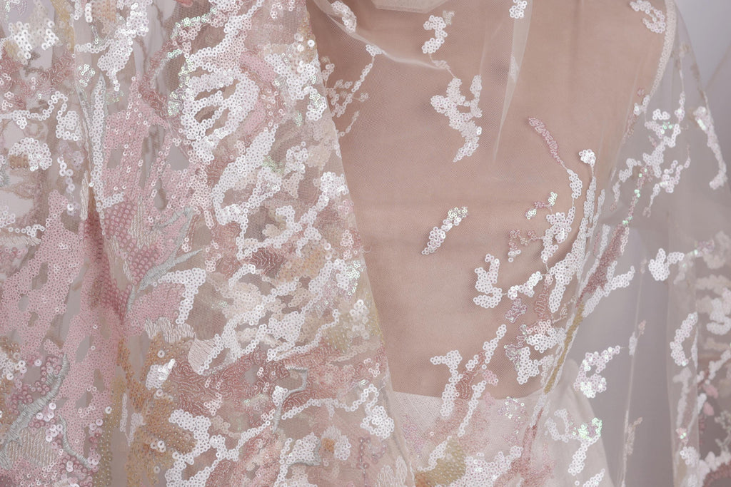 a close-up view of a delicate, lace-like fabric with a floral pattern. The fabric appears to be made of sheer material, giving it a soft and delicate appearance. The intricate design and texture of the fabric create a visually appealing and elegant look.