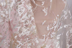 a close-up view of a delicate, lace-like fabric with a floral pattern. The fabric appears to be made of sheer material, giving it a soft and delicate appearance. The intricate design and texture of the fabric create a visually appealing and elegant look.