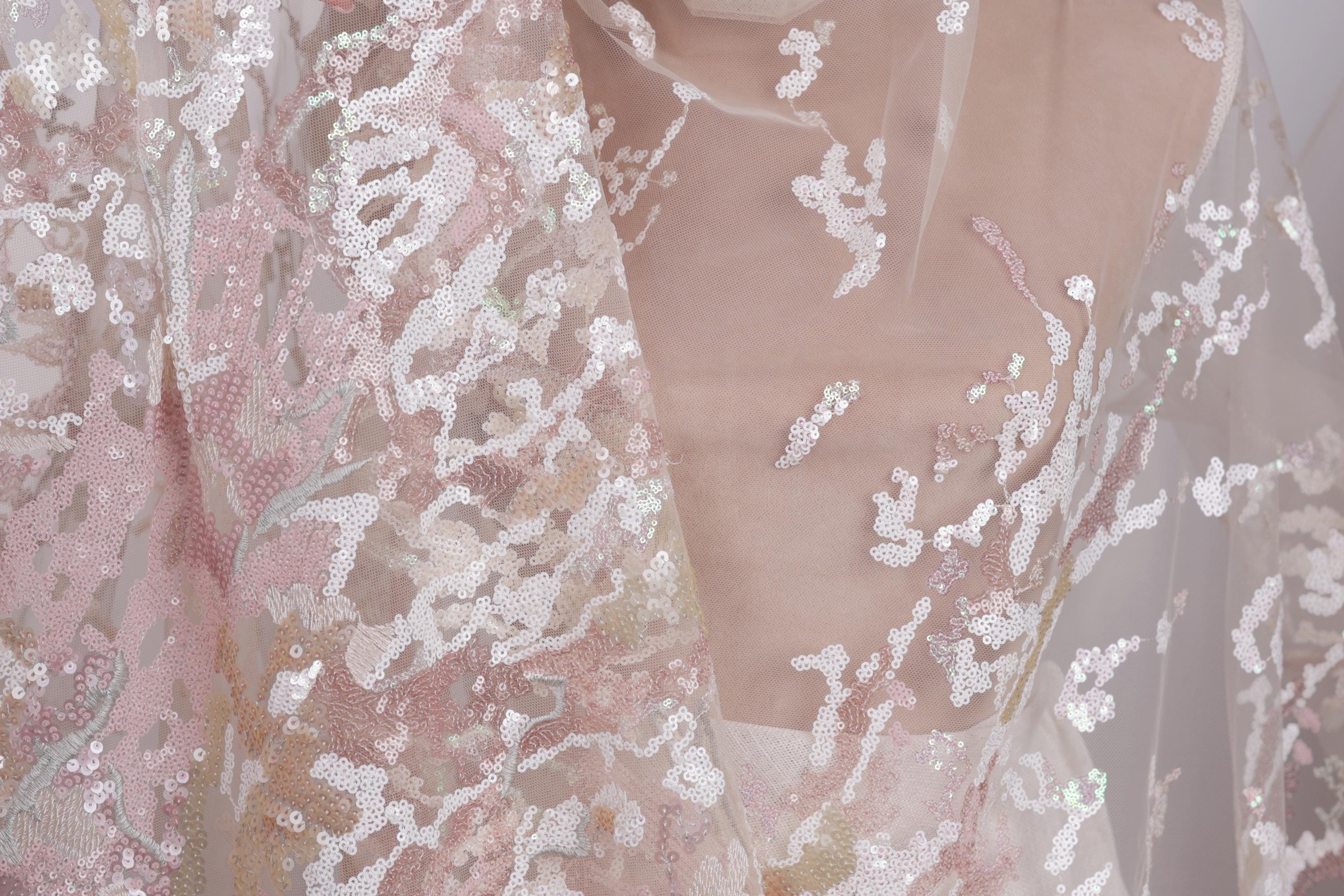 a close-up view of a delicate, lace-like fabric with a floral pattern. The fabric appears to be made of sheer material, giving it a soft and delicate appearance. The intricate design and texture of the fabric create a visually appealing and elegant look.