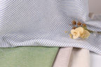 a close-up view of a fabric with blue and white striped patterns, with a small yellow flower resting on top of it.