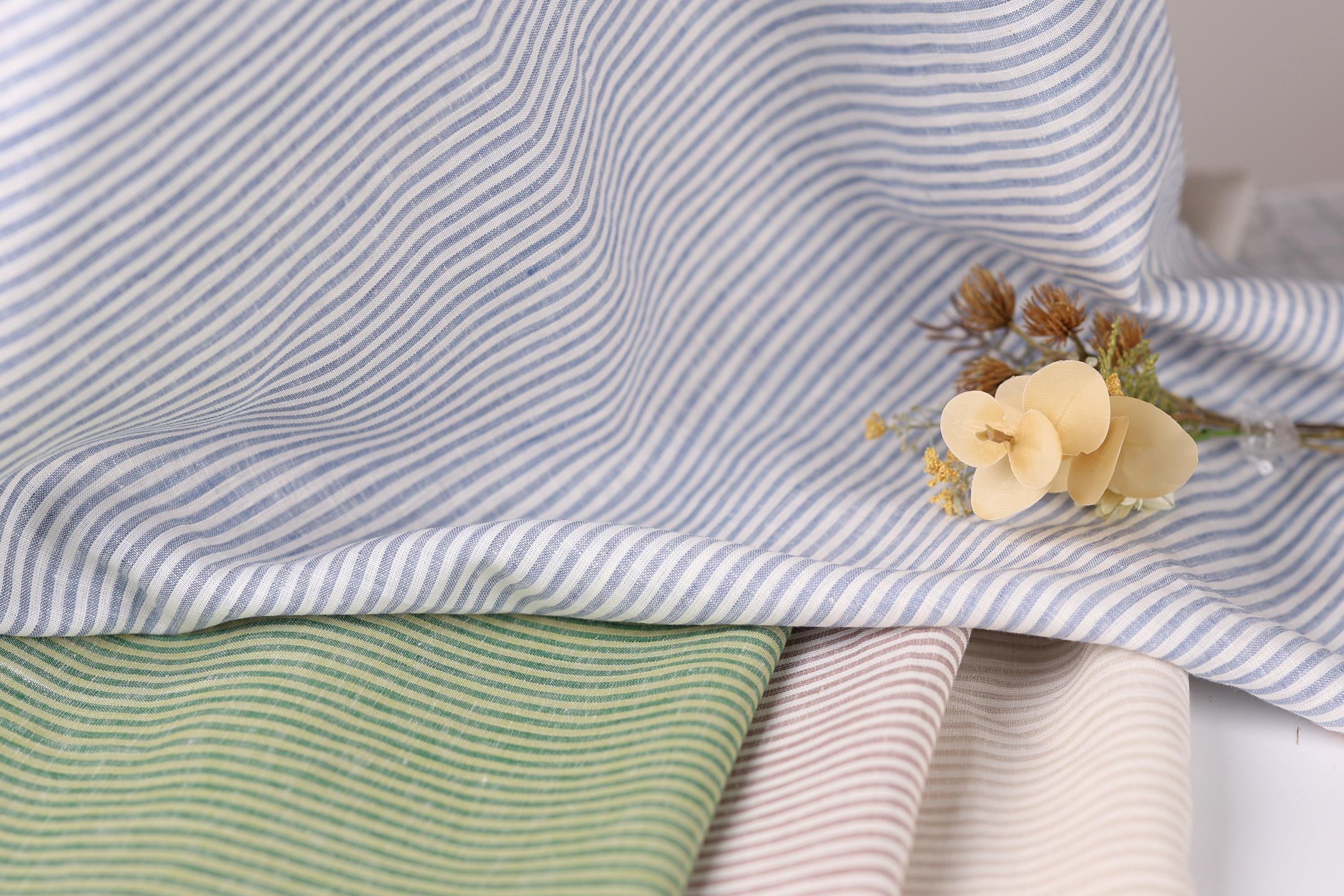 a close-up view of a fabric with blue and white striped patterns, with a small yellow flower resting on top of it.