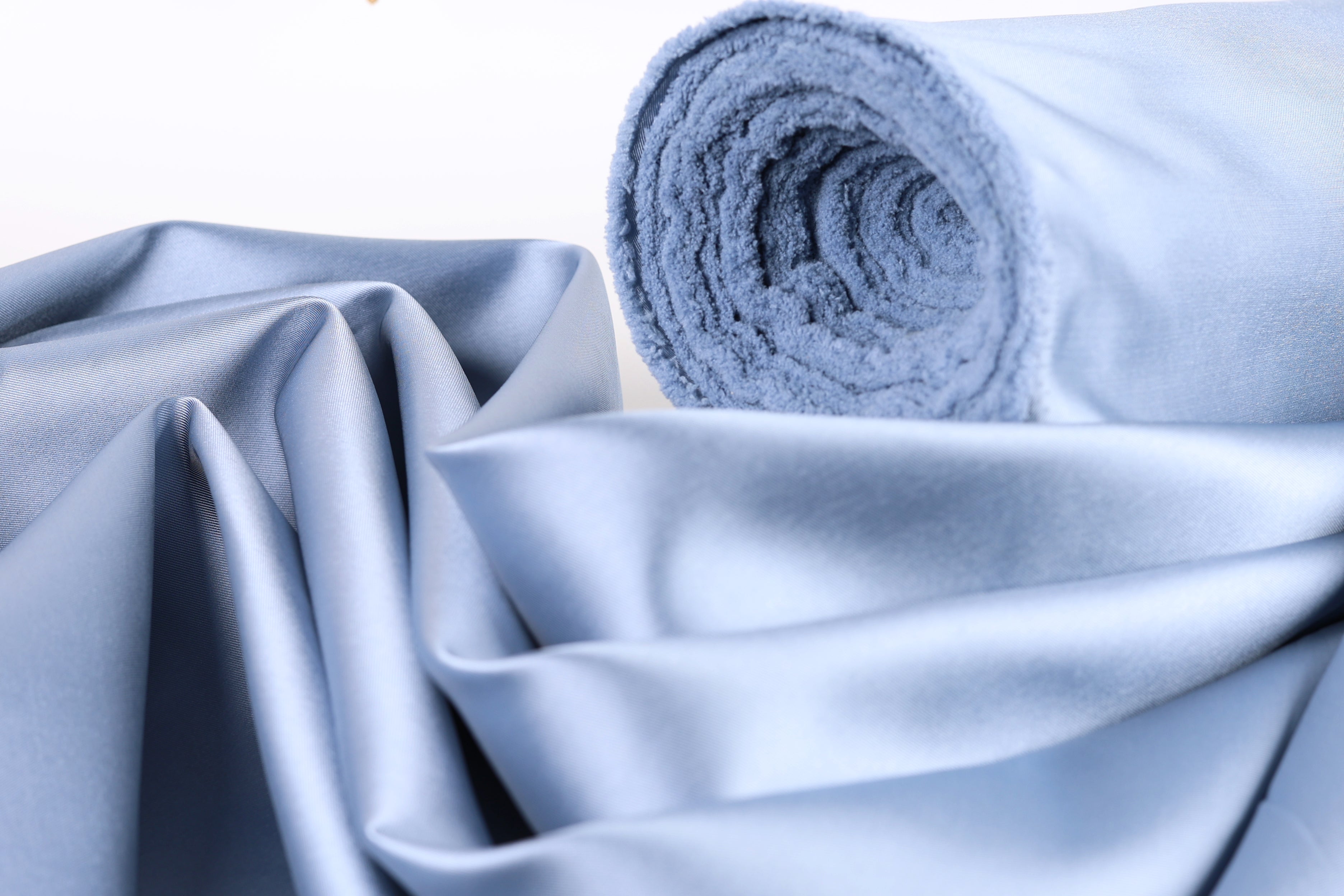 a close-up view of a blue fabric, possibly silk or satin, with a rolled-up end visible.