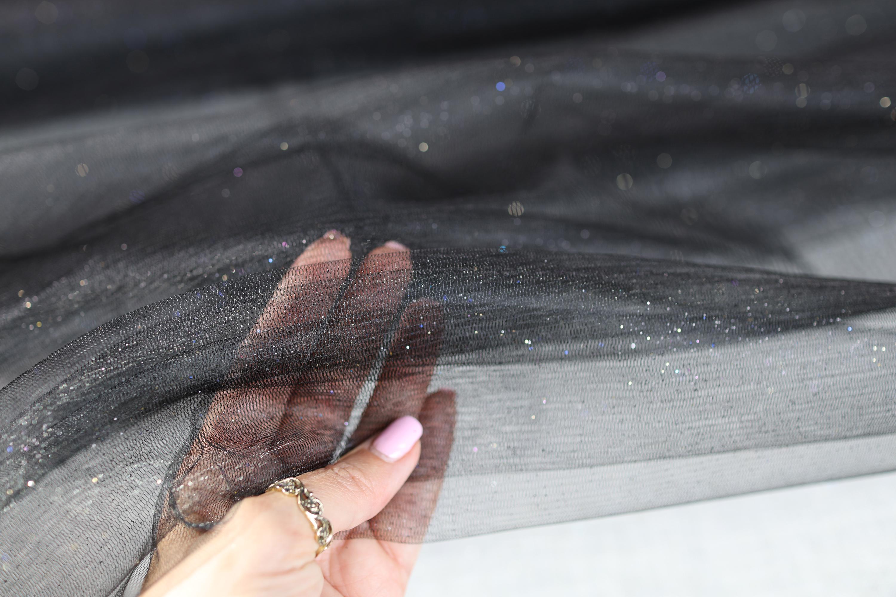 a woman's hand holding a piece of sheer fabric