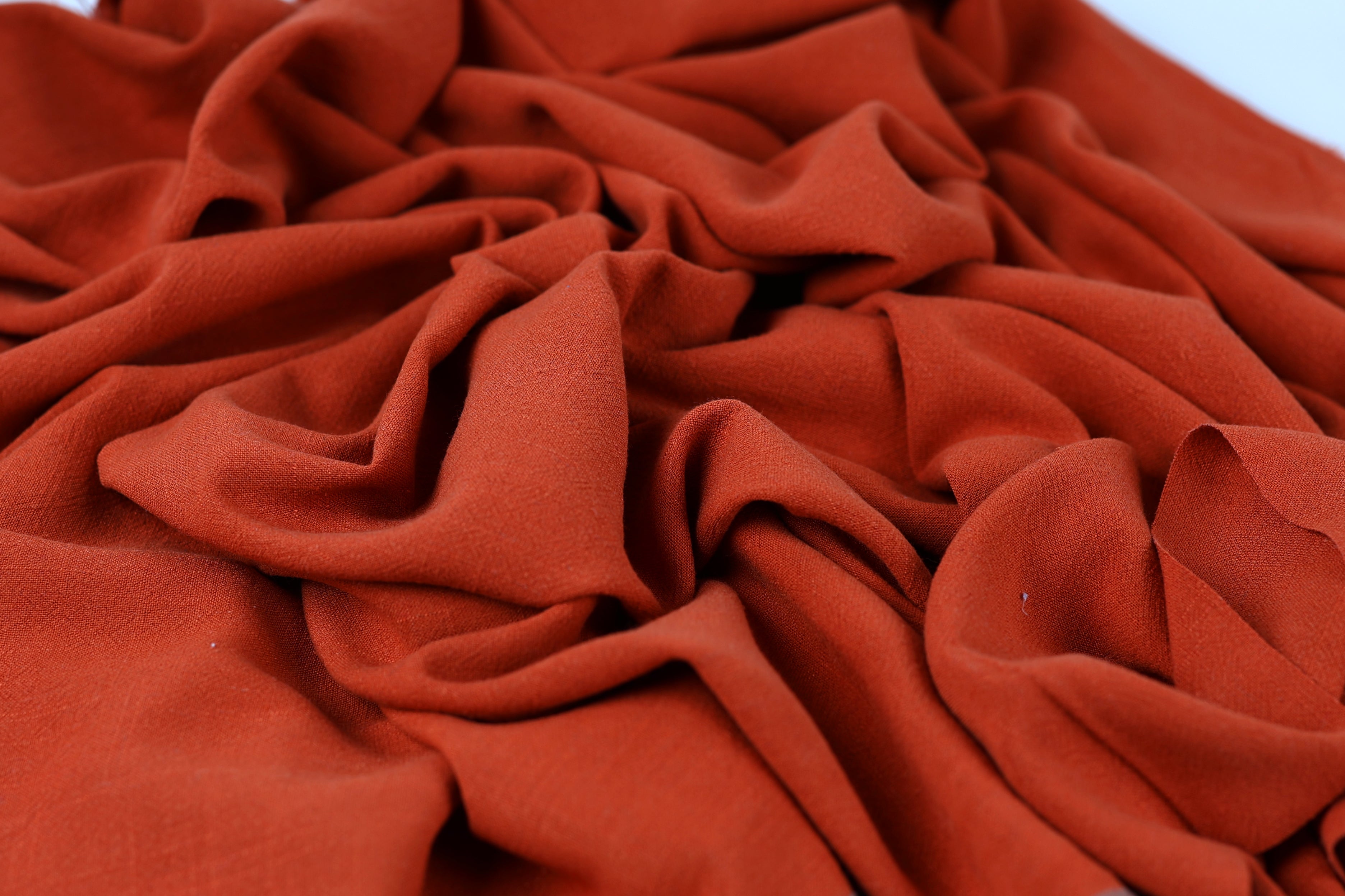 The image is a close-up of a crumpled, orange-colored fabric, possibly a piece of clothing or textile.