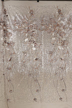 a close-up view of a fabric with a floral pattern, including various shades of pink and white flowers and leaves. The fabric appears to be made of a shiny, sequined material, giving it a sparkling and elegant appearance.
