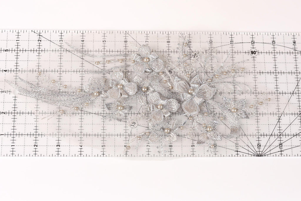 a close-up view of a decorative silver flower arrangement on a ruler.