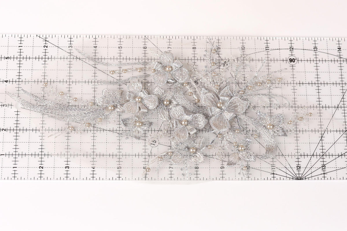 a close-up view of a decorative silver flower arrangement on a ruler.