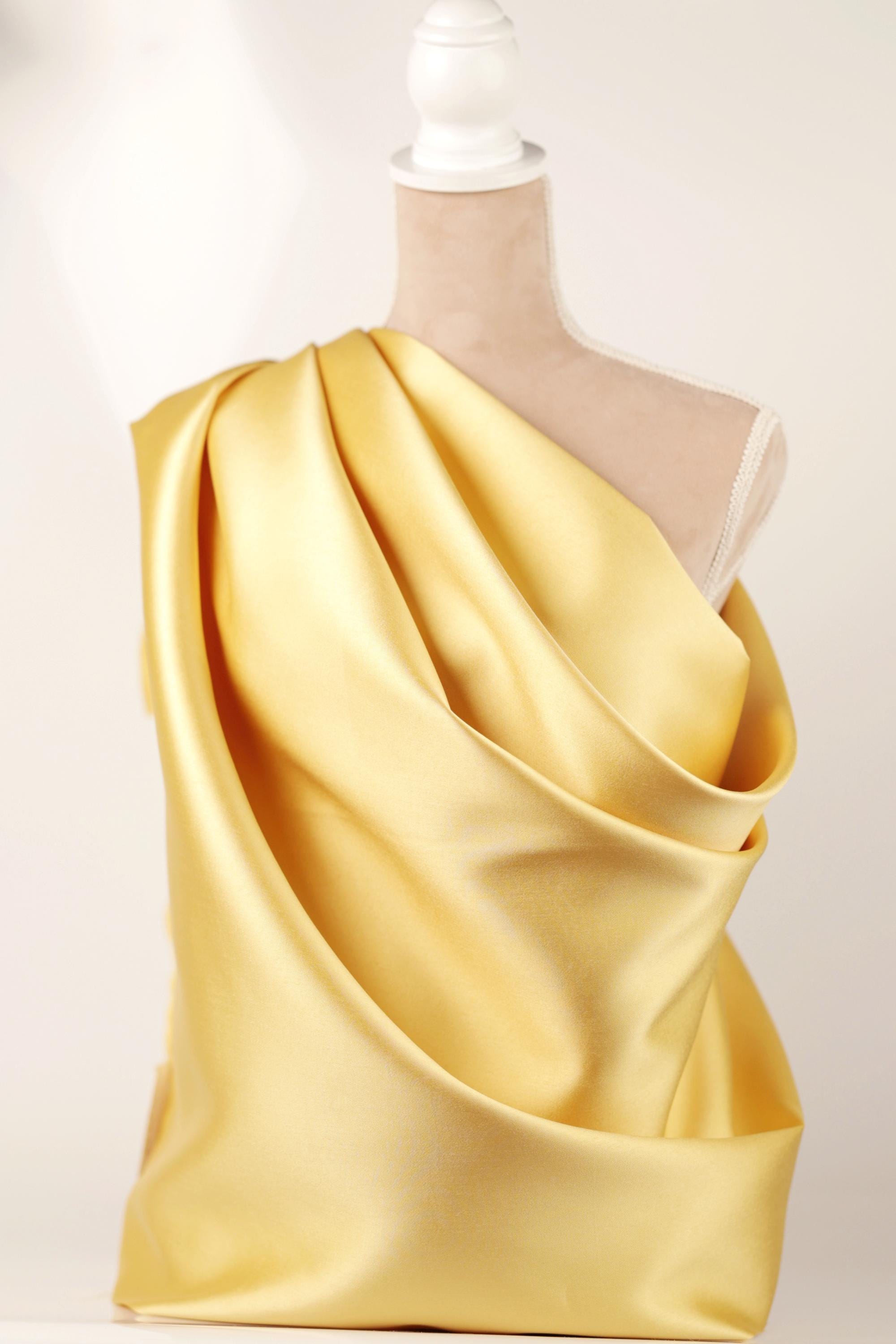 A mannequin wearing a yellow draped fabric dress.