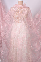a close-up view of a delicate, pink lace fabric with intricate floral patterns. The fabric appears to be a sheer, sheer lace material, which is often used for creating dresses or other delicate garments. The image does not contain any text or other discernible objects, and the focus is solely on the lace fabric.