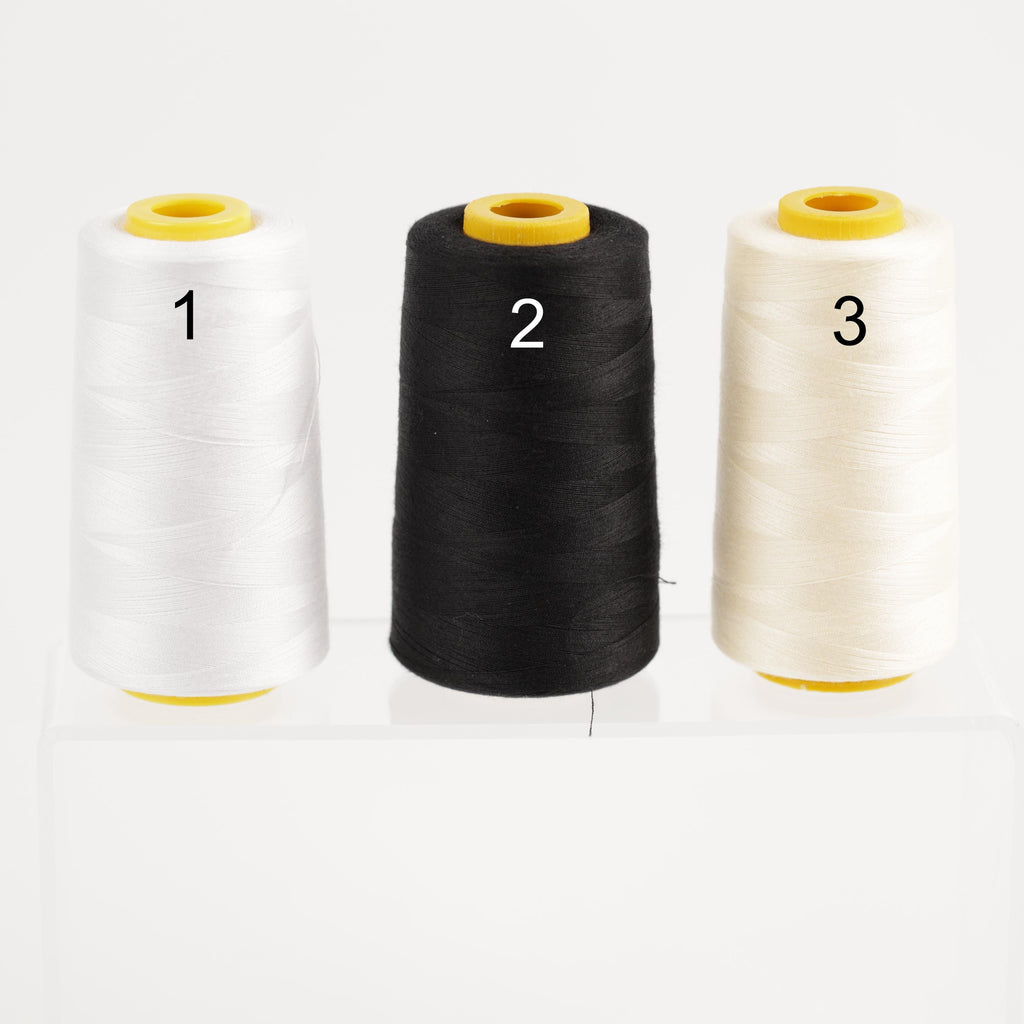 three spools of thread, each with a different color: white, black, and beige.