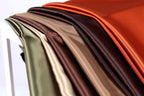 A close-up view of a collection of colorful fabric swatches, including shades of green, brown, orange, and red, arranged in a visually appealing manner.