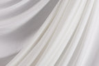 The image is a close-up of a white fabric, possibly a sheer or sheer-like material, with a soft, flowing texture.