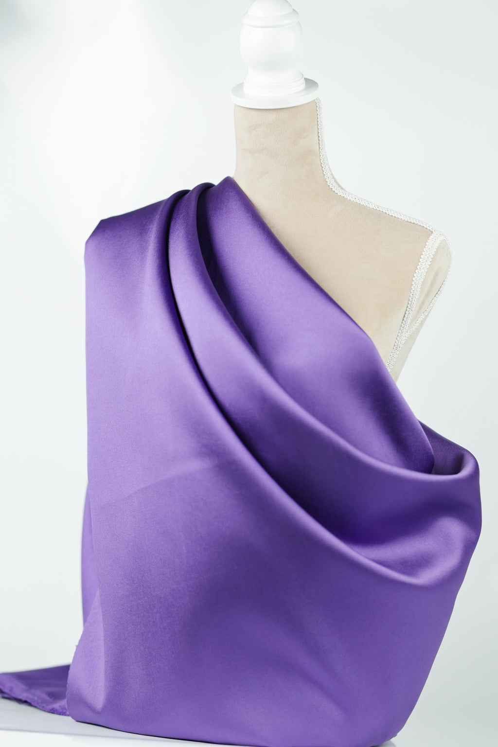 A mannequin is wearing a purple satin fabric draped over its body.