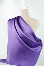 A mannequin is wearing a purple satin fabric draped over its body.