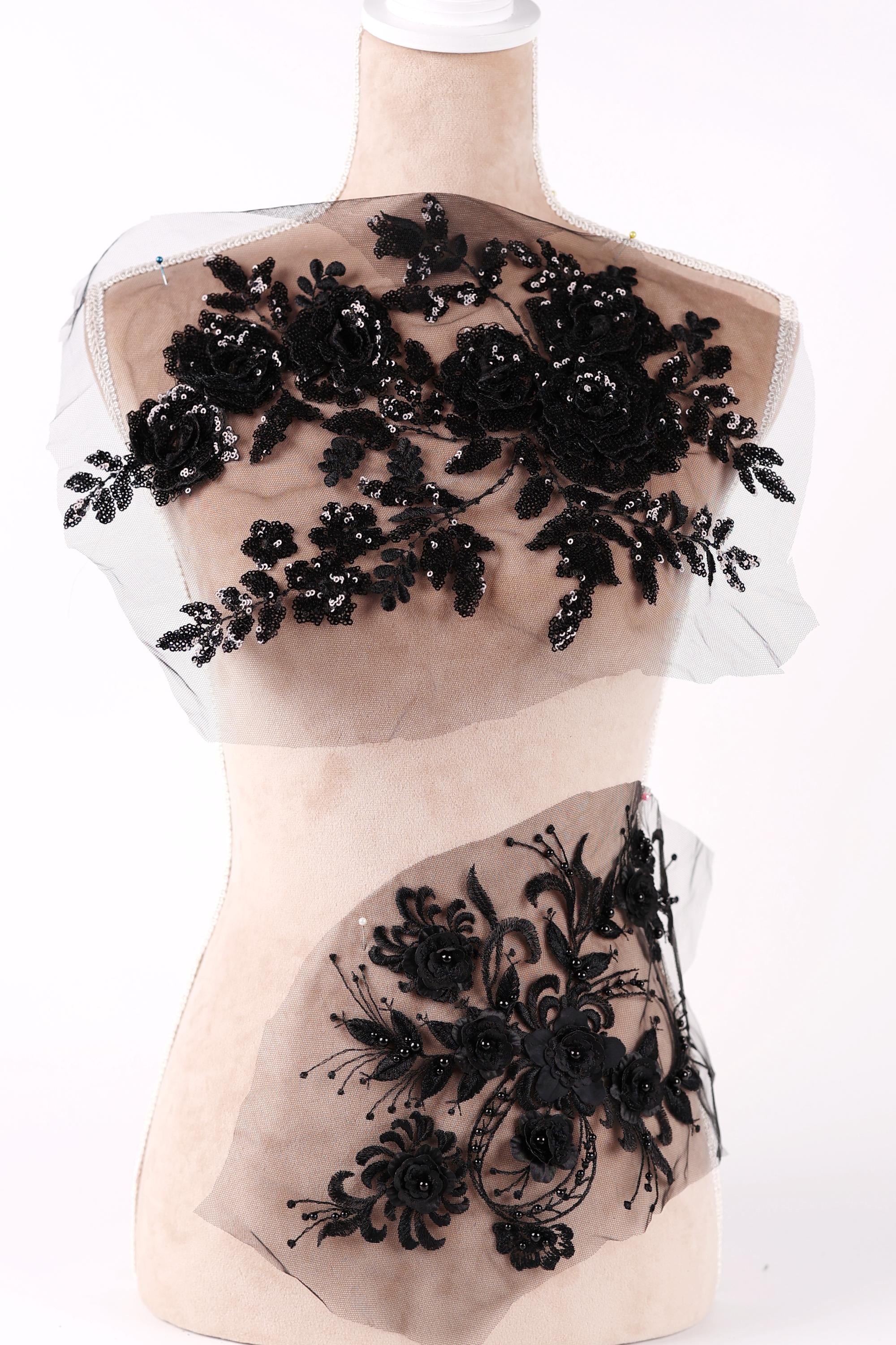 A mannequin torso with a black floral lace overlay, featuring a variety of black flowers and leaves.