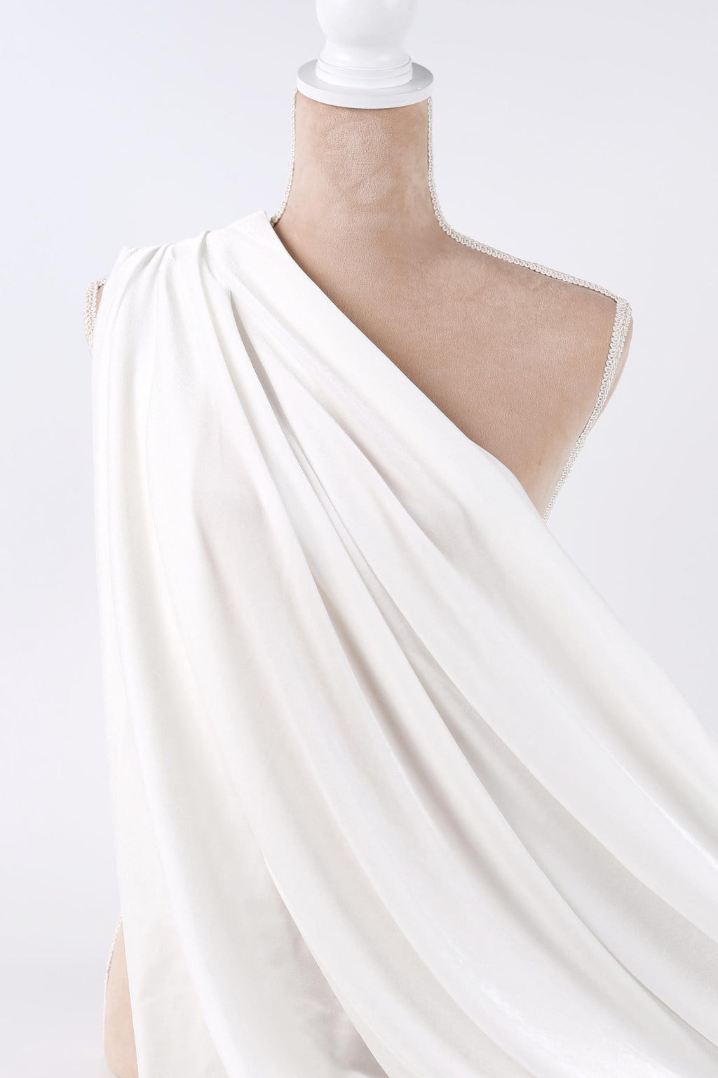 A mannequin wearing a white draped garment against a plain background.