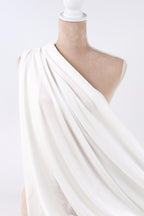A mannequin wearing a white draped garment against a plain background.