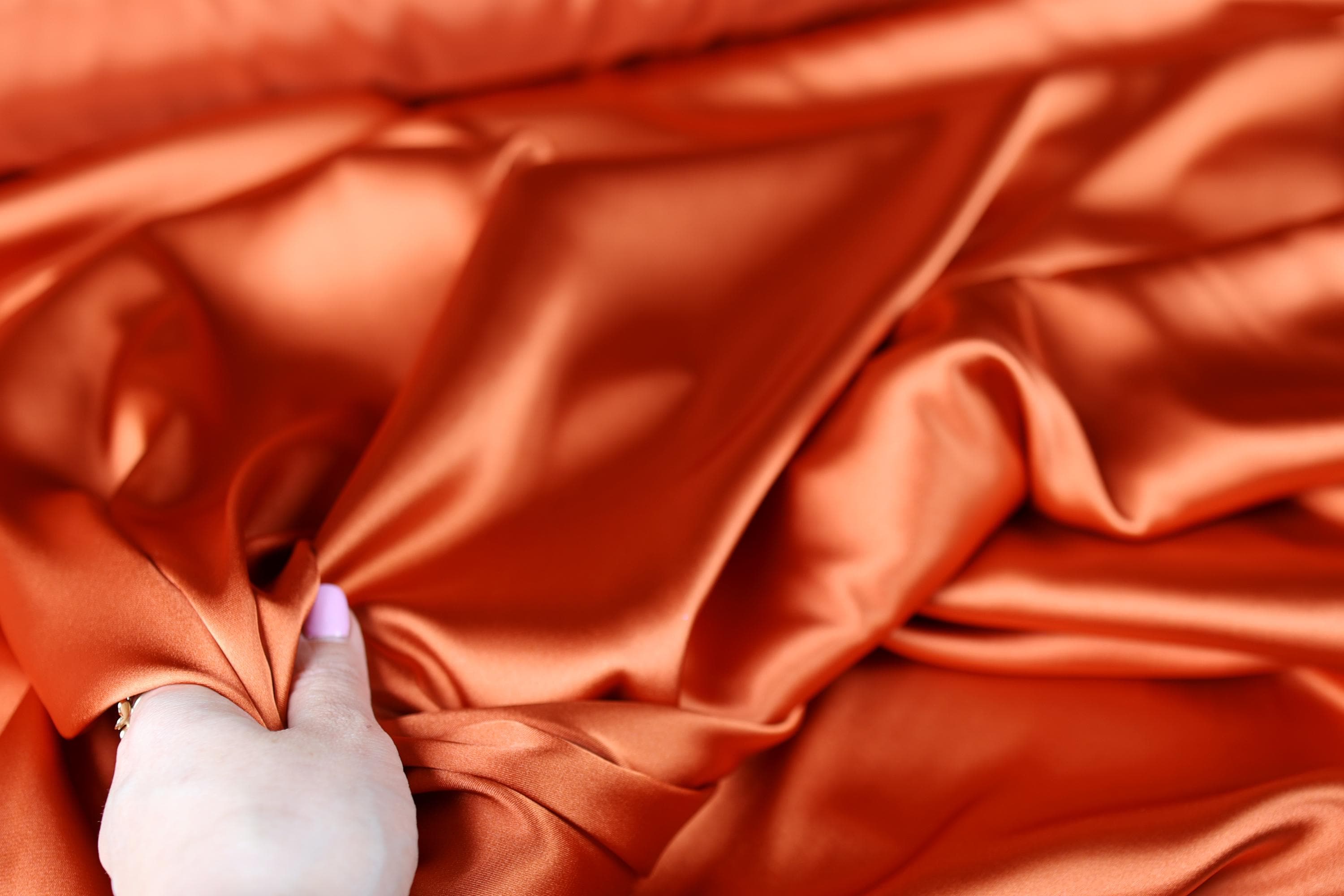 a person&#39;s hand on a satin material