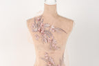 A mannequin with a delicate floral embroidered on its back, featuring pink flowers and leaves.