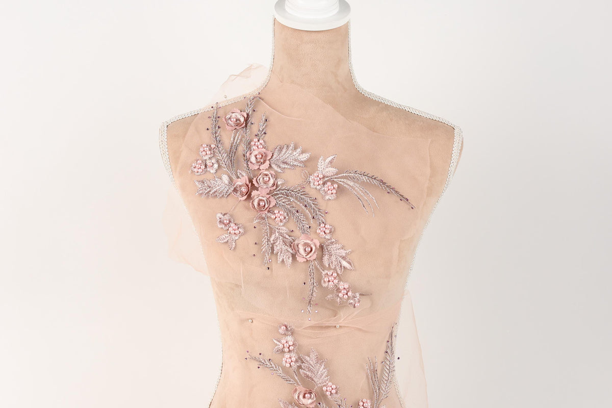A mannequin with a delicate floral embroidered on its back, featuring pink flowers and leaves.