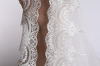 A close-up view of a delicate, white lace wedding veil with intricate floral patterns.
